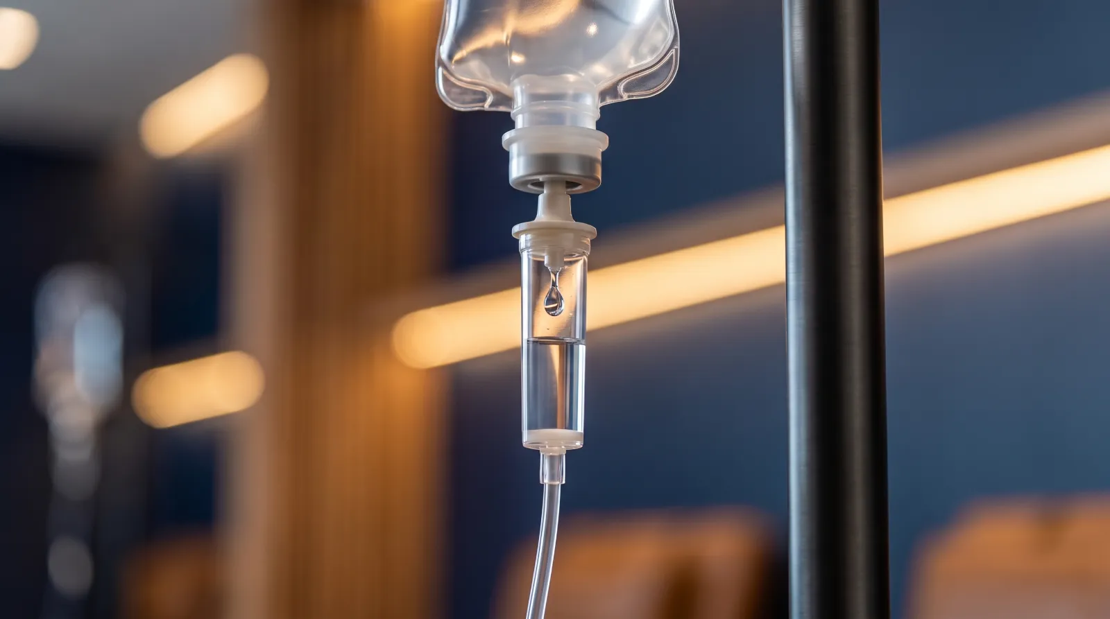 Concept rendering of an IV drip chamber against warm gold clinic lights.